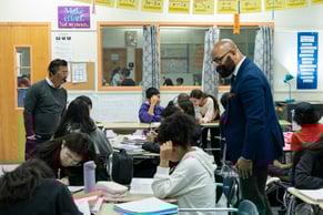 ANet Coach Rashid Johnson and a middle school teacher at The Renaissance Charter School observe middle school students and they work on a lesson at their desks.